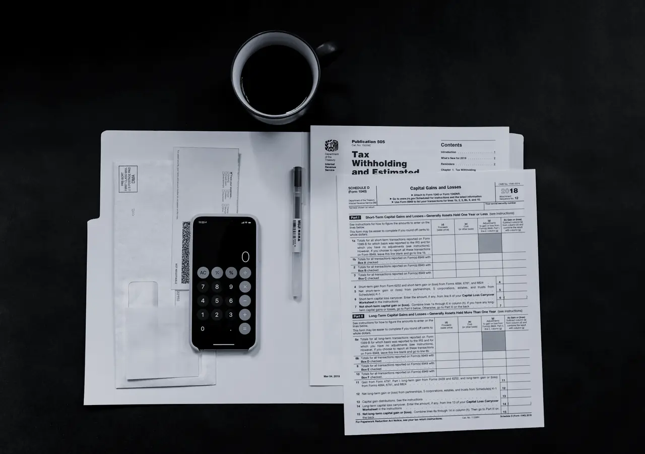 Tax forms, a calculator and coffee on a dark desk